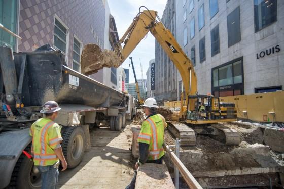 Construction workers operate excavation equipment at Market Street Station site on 4th Street.