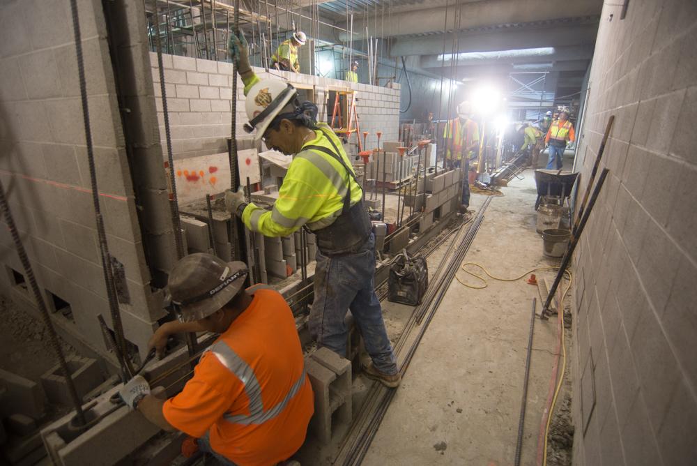 Construction workers build cinderblock walls inside Union Square station tunnel.
