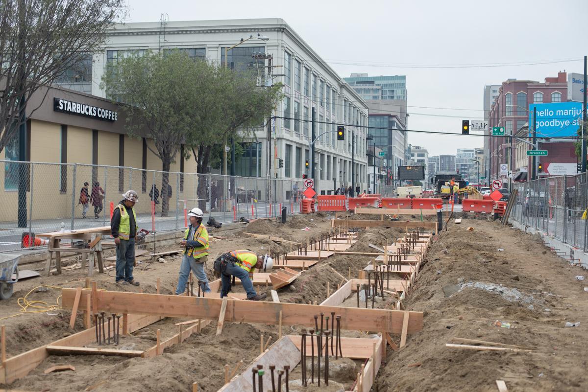 Construction workers in safety gear building concrete foundation forms for the Central Subway project in San Francisco.