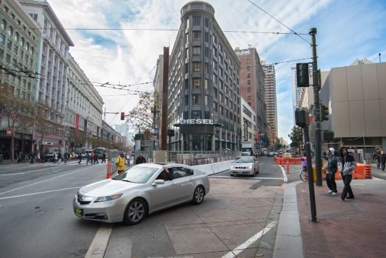Silver sedan on Market Street at 4th Street intersection with closed sidewalk and traffic barriers visible.