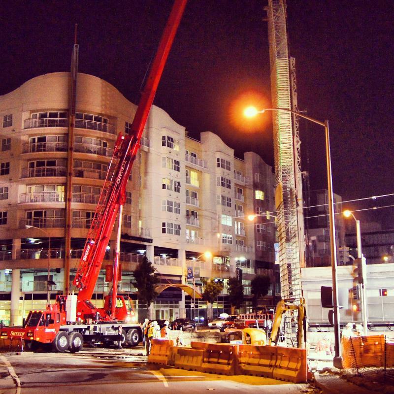 Night construction scene with red crane and drilling equipment at urban tunnel project site.