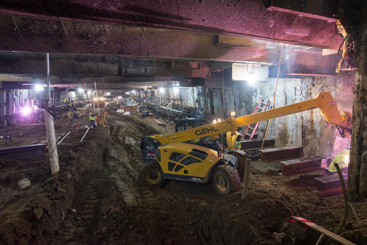 Yellow GEHL telehandler operating in underground construction site at Union Square station with welding and steel work visible.