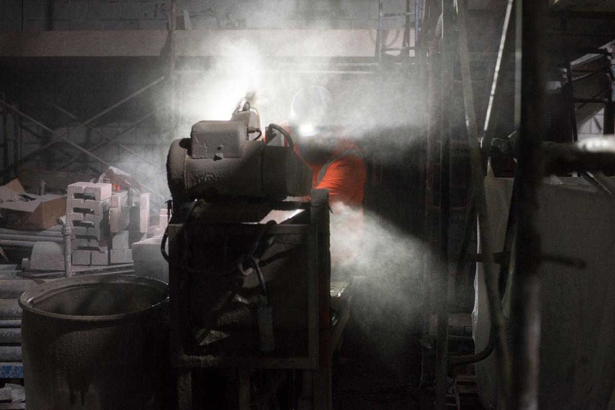 Worker using wet saw to cut cinderblocks for station construction at night.