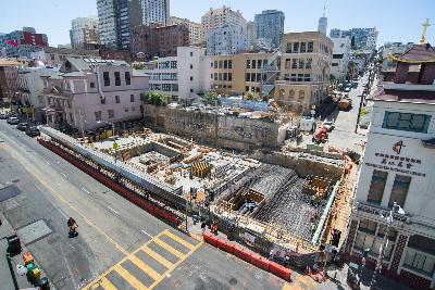 Construction site for future Chinatown Station with roof deck and surrounding San Francisco cityscape.
