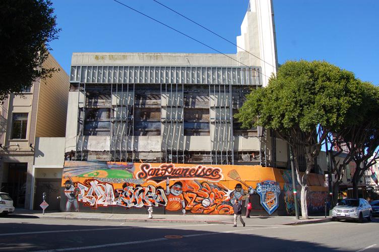 San Francisco street corner with colorful mural on building facade and modern architecture above.