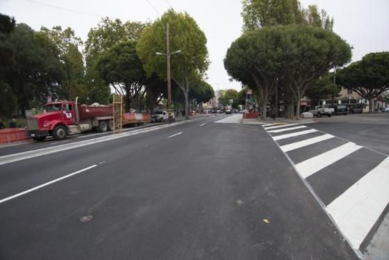Wide street with mature trees, crosswalk, fire truck, and utility work equipment along Columbus Avenue.