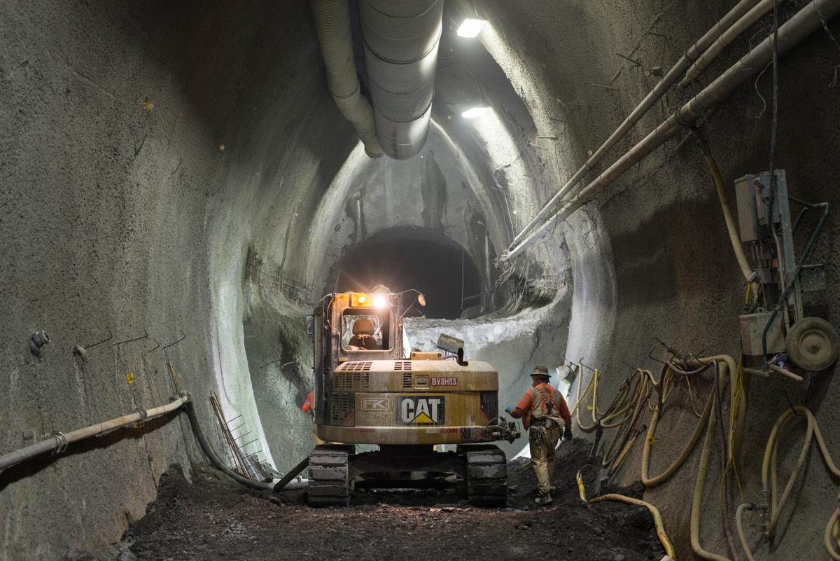 CAT excavator operates inside tunnel during platform cavern excavation work.