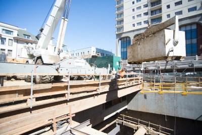 Chinatown Station construction site with excavation equipment and dewatering infrastructure visible.