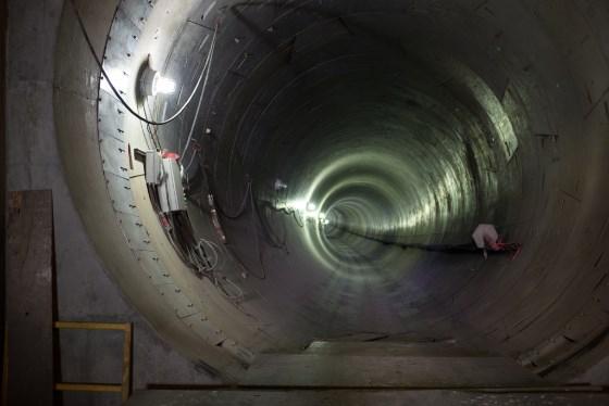 Interior view of concrete tunnel with construction equipment and lighting extending into distance