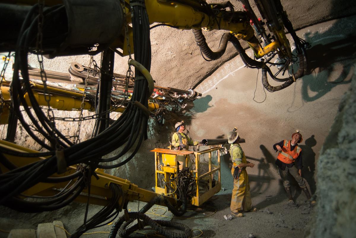 Workers operate drilling equipment in underground tunnel construction near Stockton Street.