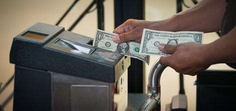 Person inserting dollar bills into a Muni fare payment machine.