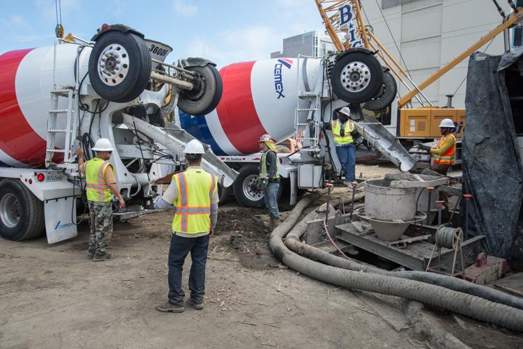 Construction workers operate cement mixer trucks at Yerba Buena/Moscone Station during concrete delivery and pouring operations.