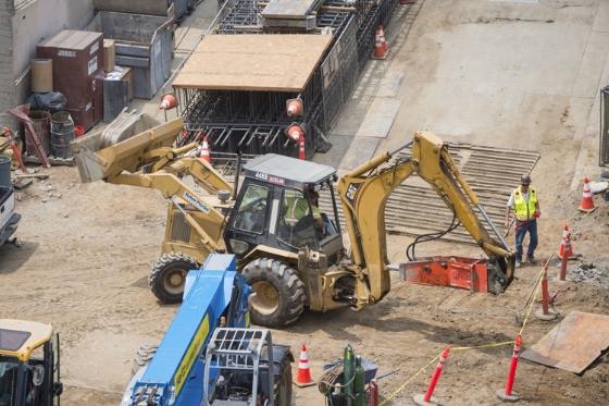 Construction equipment and workers at future Chinatown Station excavation site with rebar visible.