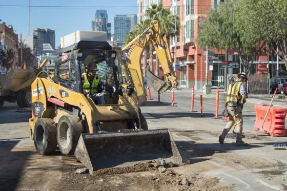 Construction workers operate heavy equipment on 4th Street during Central Subway project roadway preparation.