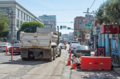 Dump truck parked on urban street with construction barriers and equipment visible