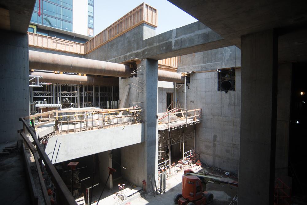 Construction site showing concrete structural columns and steel bracing being removed from an underground transit station headhouse.