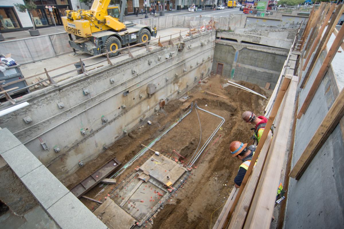 Construction excavation at Union Square showing workers and temporary bracing in deep pit with equipment above.