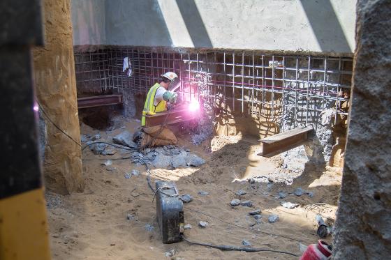 Worker welding steel reinforcement at Union Square Market Street station construction site.