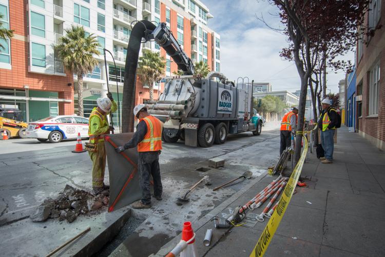 Workers operate a vacuum truck to excavate utilities on 4th Street in San Francisco.