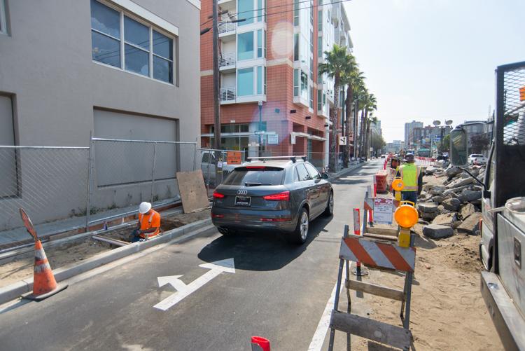 Construction zone on 4th Street with traffic control, equipment, and multi-story buildings under development.