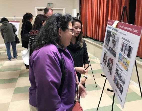 Visitors examine project display boards at an indoor public meeting about the L Taraval Improvement Project.