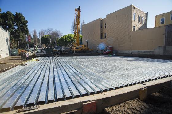 Metal roof deck installed over North Beach construction site with crane and buildings visible