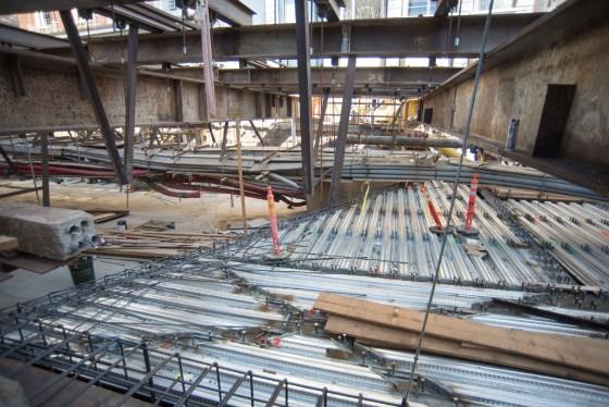 Construction site with corrugated steel sheets and structural steel framing for transit station roof.