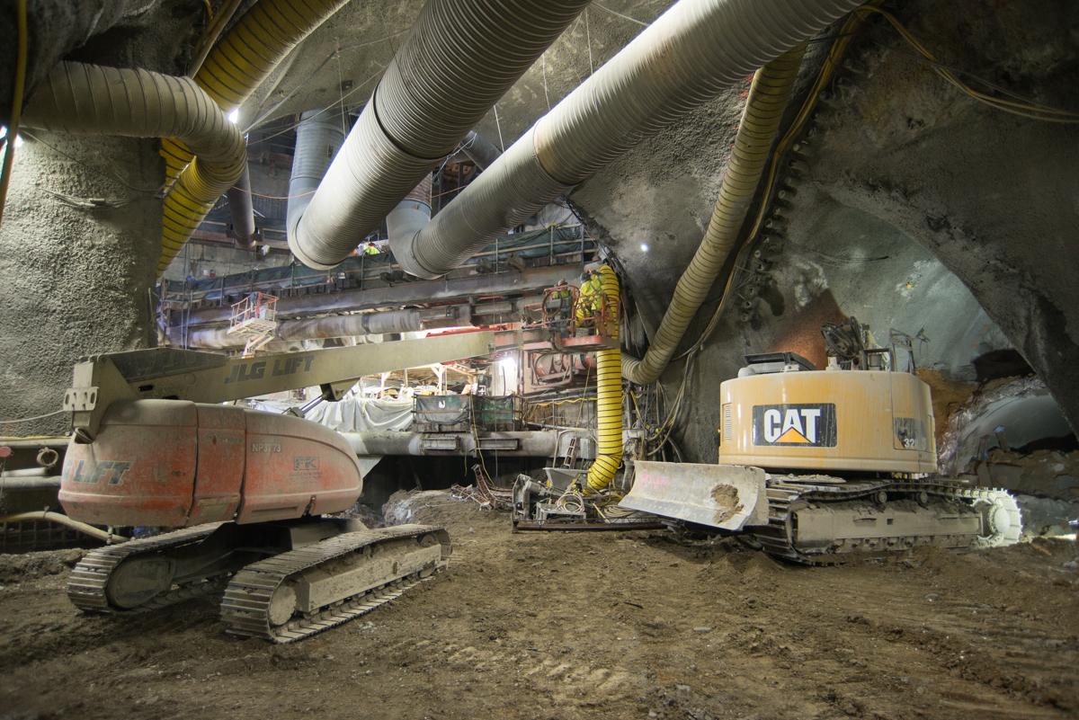 Excavation equipment and ductwork inside an underground transit station cavern under construction.