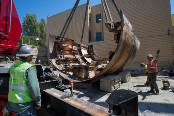 Crane lifting large curved metal tunnel boring machine segment at North Beach retrieval shaft.