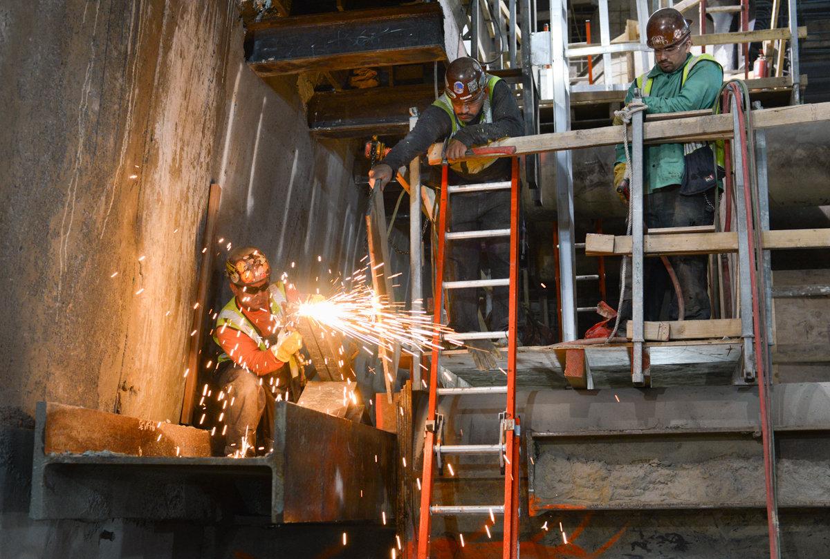 Worker welding metal framework on temporary bracing at Union Square station mezzanine level.