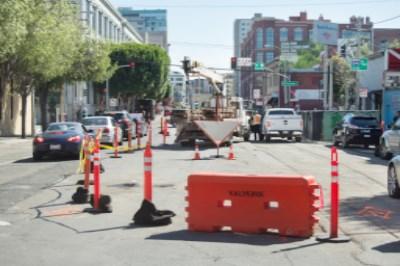 Street intersection blocked with red traffic cones and barriers for underground utility construction work.