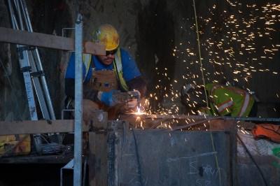 Worker in hard hat welding steel structure at night with sparks flying