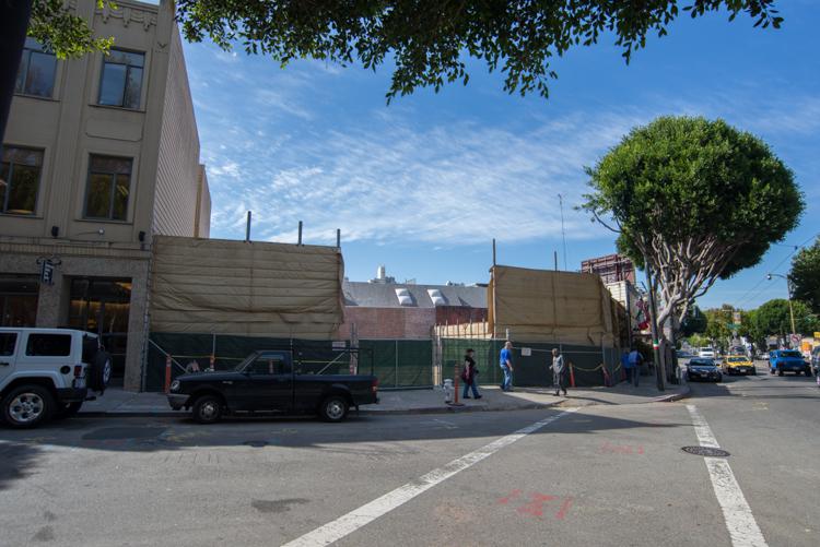 Construction site with sound barriers at Clay and Stockton intersection, San Francisco street scene with vehicles and pedestrians.