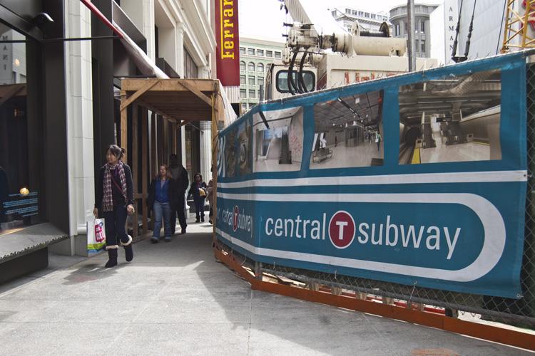 Central Subway construction site on Stockton Street with covered walkway and blue signage.