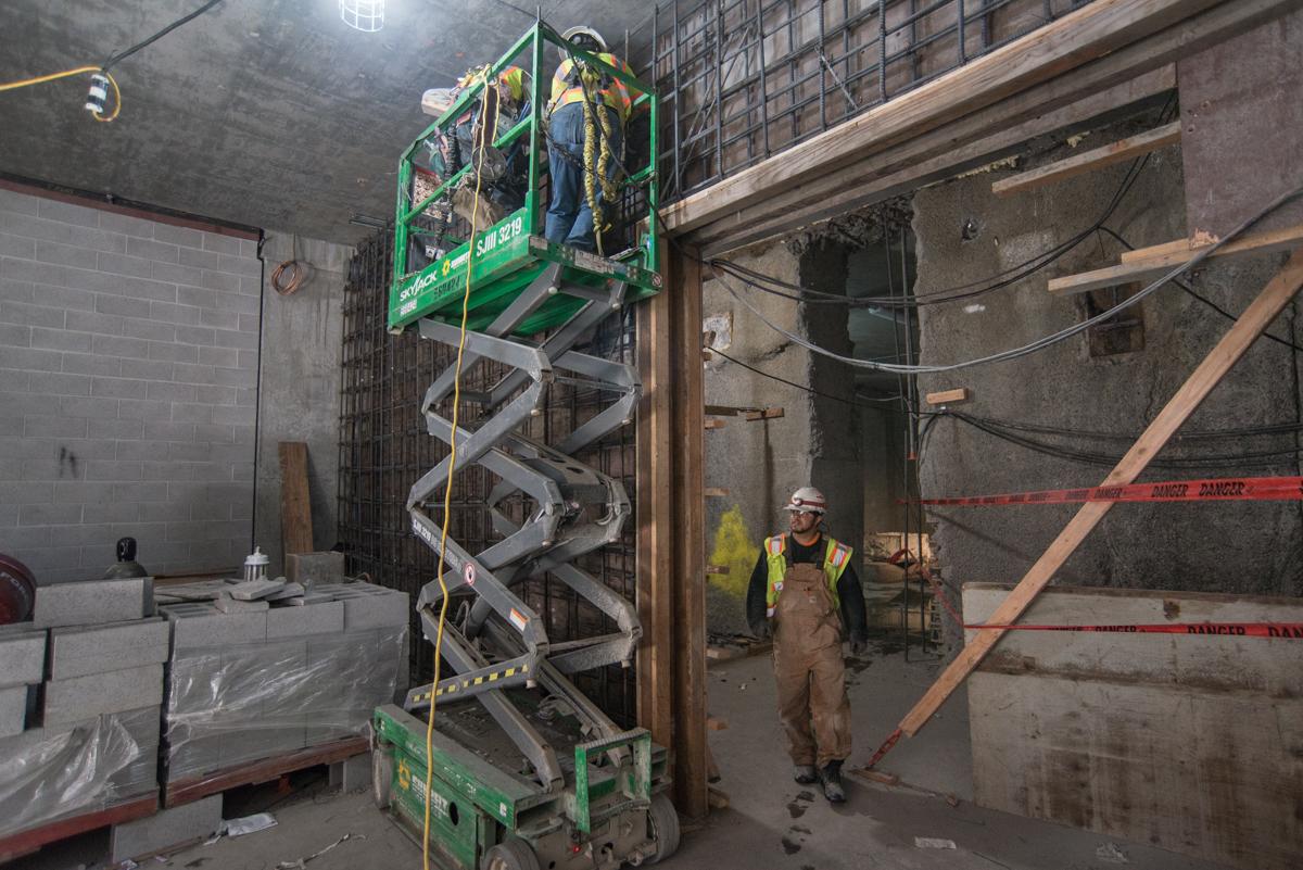 Construction worker on scissor lift at underground transit station mezzanine level during night work hours.