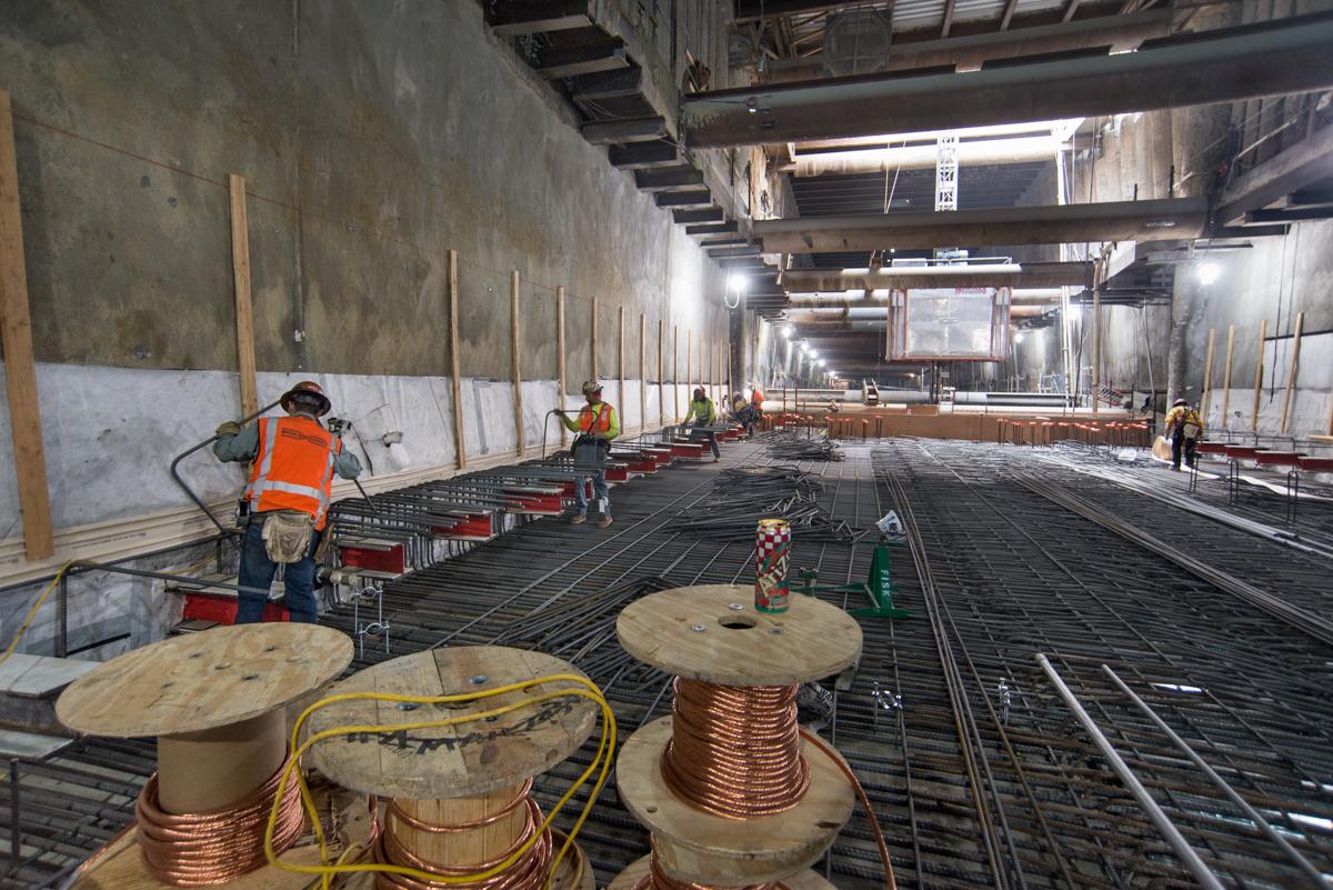 Construction workers install rebar and formwork inside underground station box at Stockton Street.