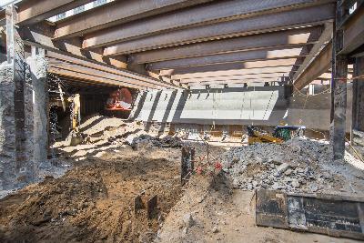 Construction site excavation at Geary and Stockton intersection with exposed soil and structural framework visible.