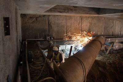 Excavation work inside Chinatown Station headhouse with large metal pipe and construction equipment visible.