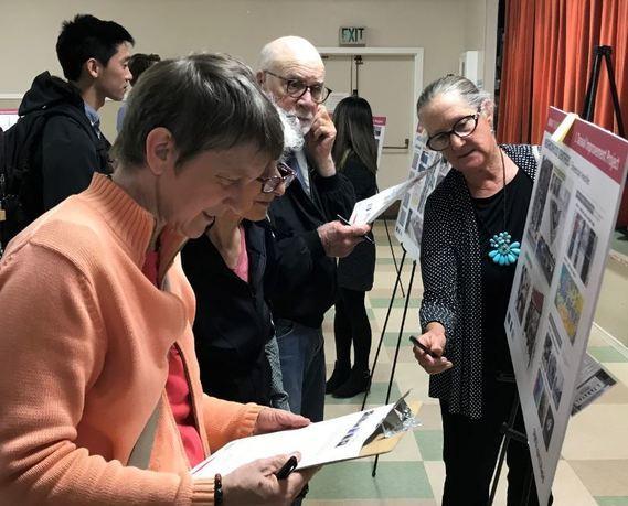 Community members examine project materials and complete surveys at an open house event.