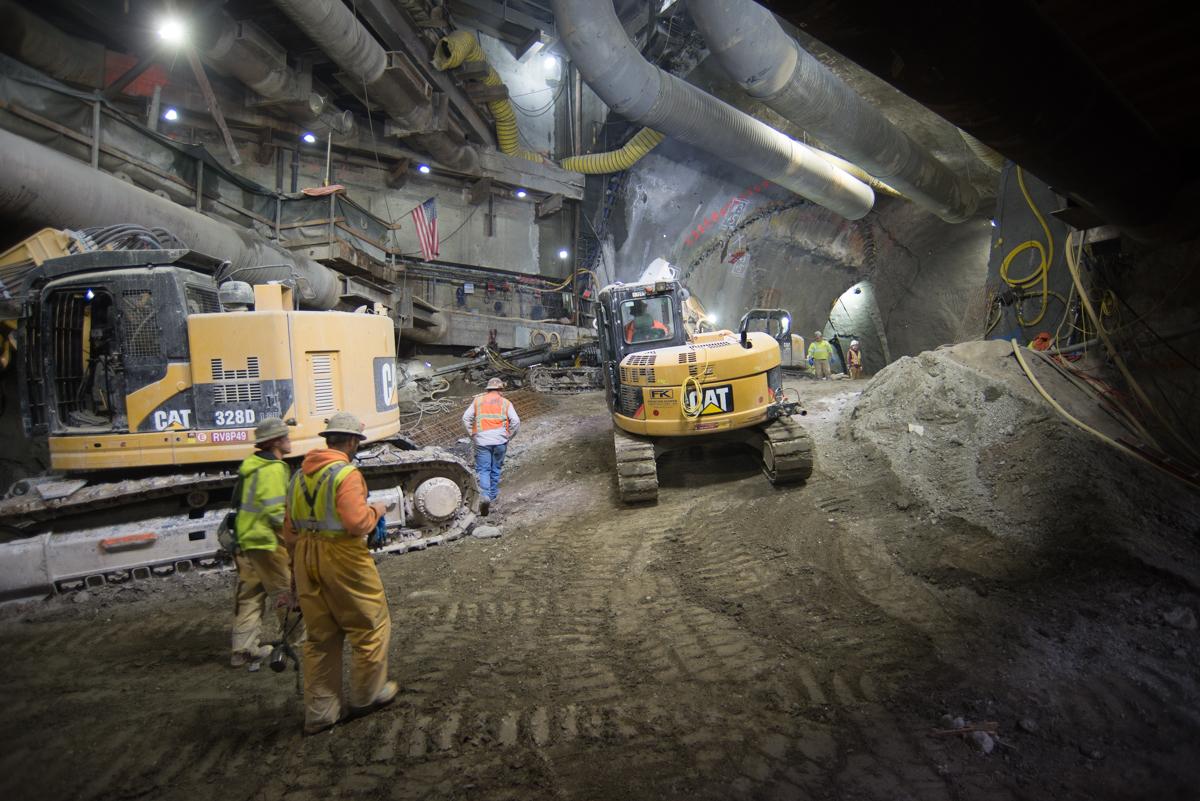 Workers and heavy equipment excavating underground at Stockton/Washington station during nighttime construction.