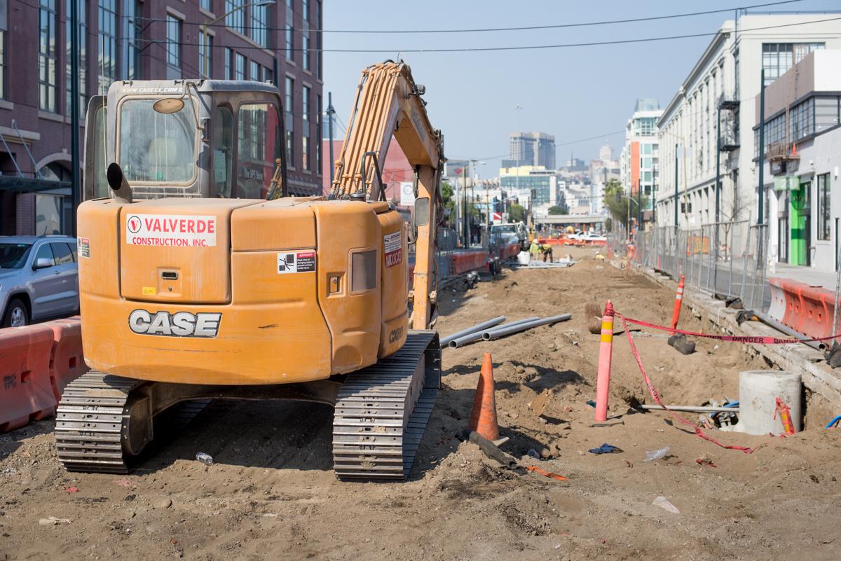 Yellow CASE excavator on 4th Street construction site with utility work and lane closures visible.