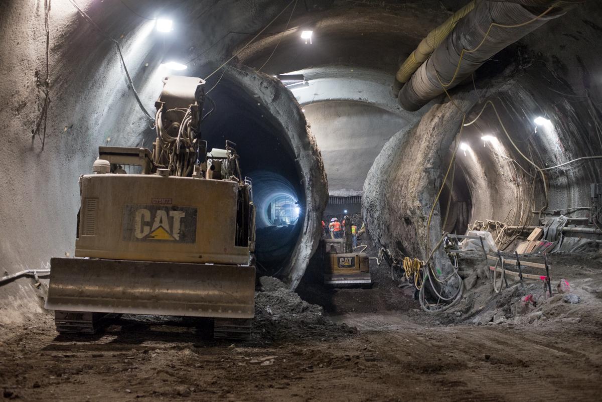 CAT excavator inside tunnel under construction with curved concrete walls and work lights