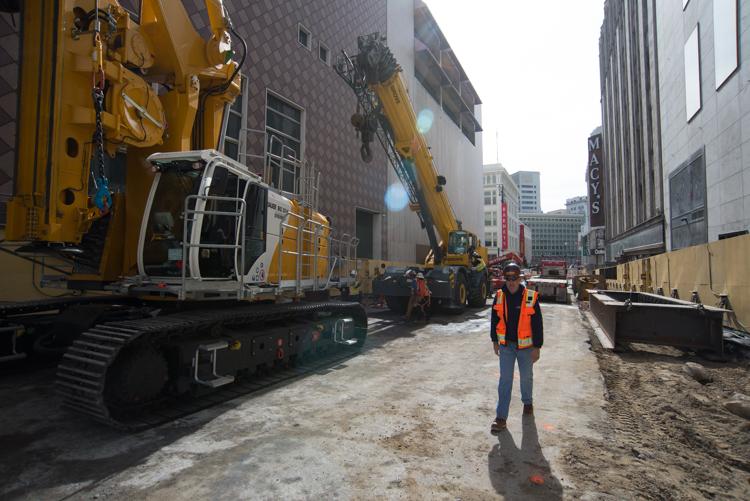 Construction equipment and workers on Stockton Street with excavator and crane machinery.