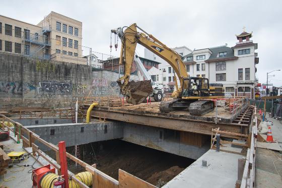 Excavation equipment operates at underground Chinatown Station construction site on city street
