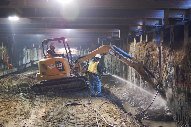 CAT excavator and worker at 4th Street launch box construction site for Central Subway tunnel project.