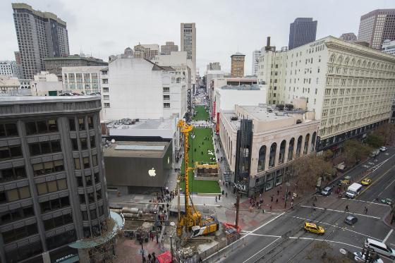 Aerial view of Stockton Street construction zone between Ellis and Post Streets with green temporary plaza, equipment, and reduced traffic lanes.