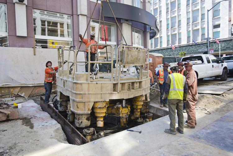 Construction crew operating drilling equipment in street excavation at Stockton and O'Farrell.