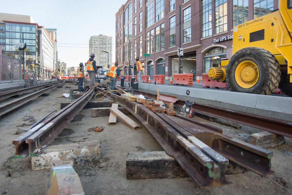 Workers install rail switch and crossover track assembly on 4th Street near Bluxome for Central Subway Project.