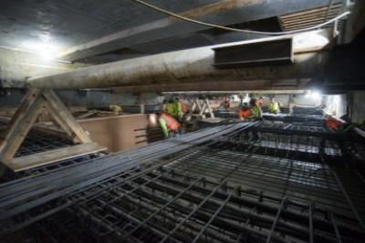 Construction workers install steel reinforcement and rebar inside underground transit station box on 4th Street.