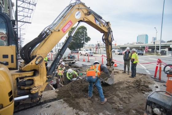 Construction crew operates excavator at 4th and Bryant Street for Central Subway utility work.